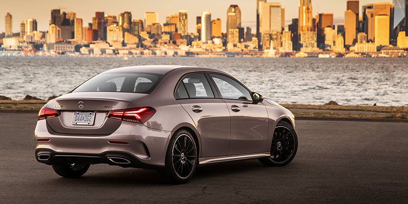 Silver Mercedes-Benz sedan parked on a waterfront roadway, viewed from the rear-left angle