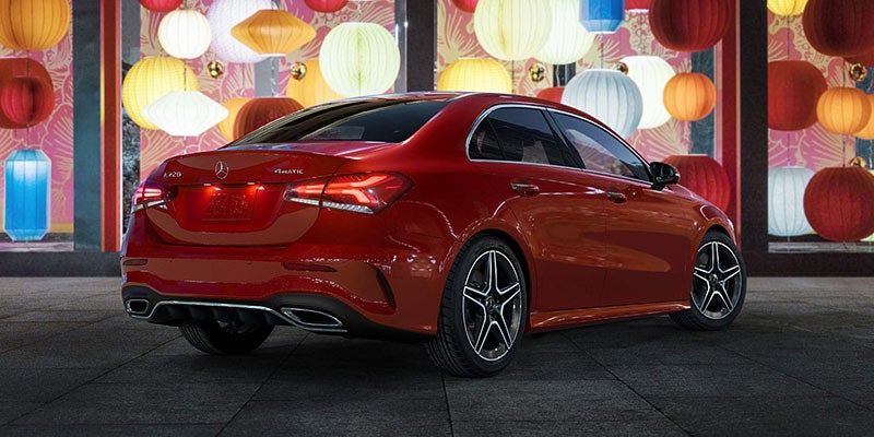 Red Mercedes-Benz sedan parked in an urban setting, viewed from the rear-left angle