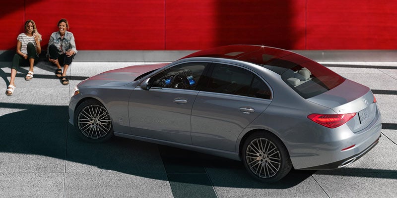 Silver Mercedes-Benz sedan viewed from above and the rear-left side, parked on a paved plaza