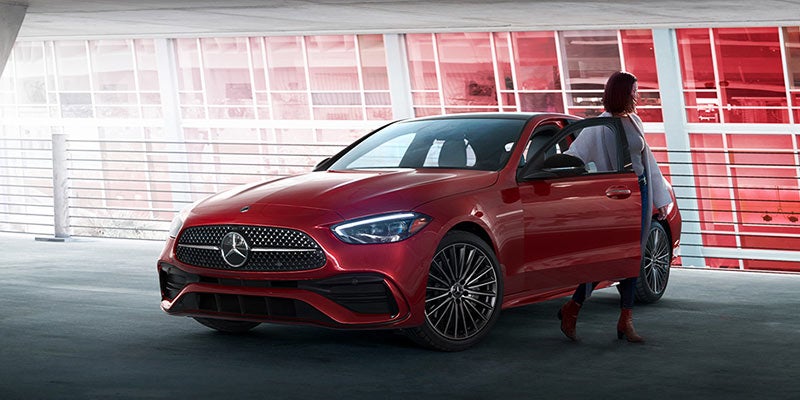 Red Mercedes-Benz sedan parked in a covered parking structure, viewed from the front-left angle