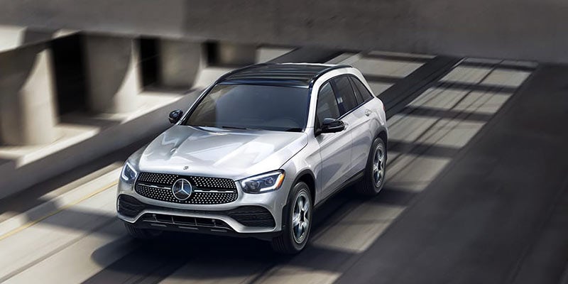silver Mercedes-Benz GLC SUV driving on an urban roadway, viewed from an elevated front angle