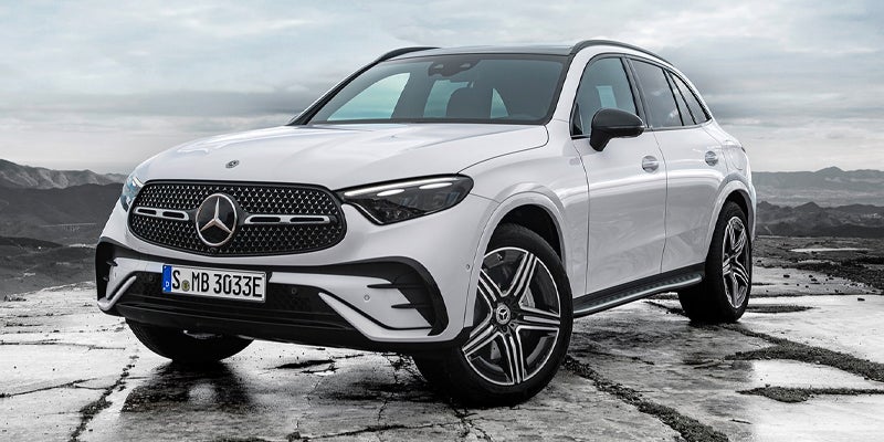 White Mercedes-Benz SUV parked on a wet, rocky surface, viewed from the front-left angle