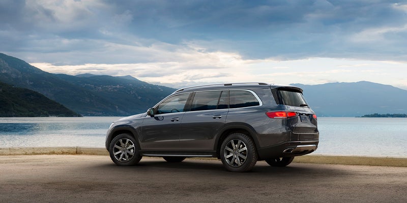 Dark gray midsize SUV parked beside a lakeside road, shown in a side profile view