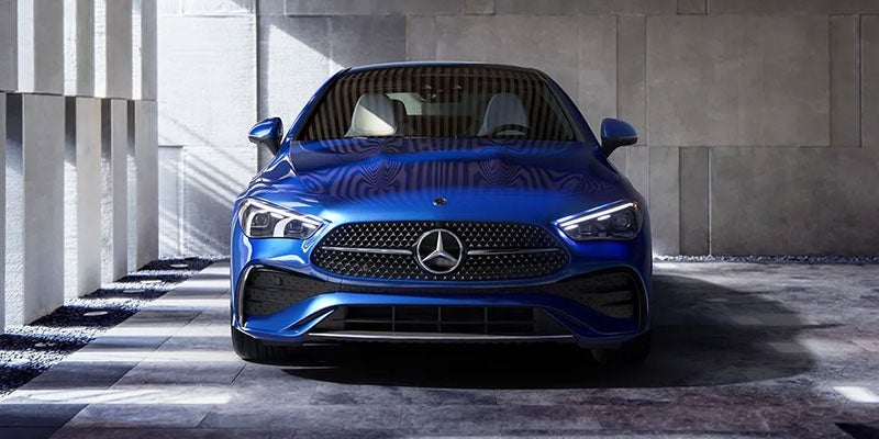 Front view of a shiny blue Mercedes-Benz sedan parked in an architectural garage with concrete block walls