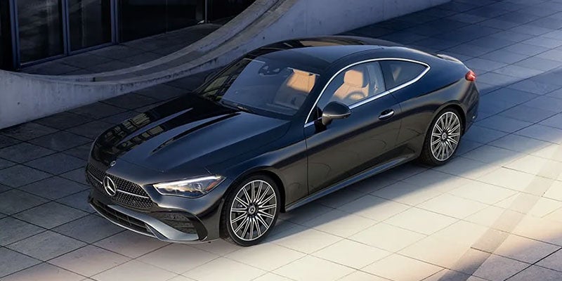 A sleek dark gray Mercedes-Benz coupe with tan interior seats parked at an angle on light gray pavement