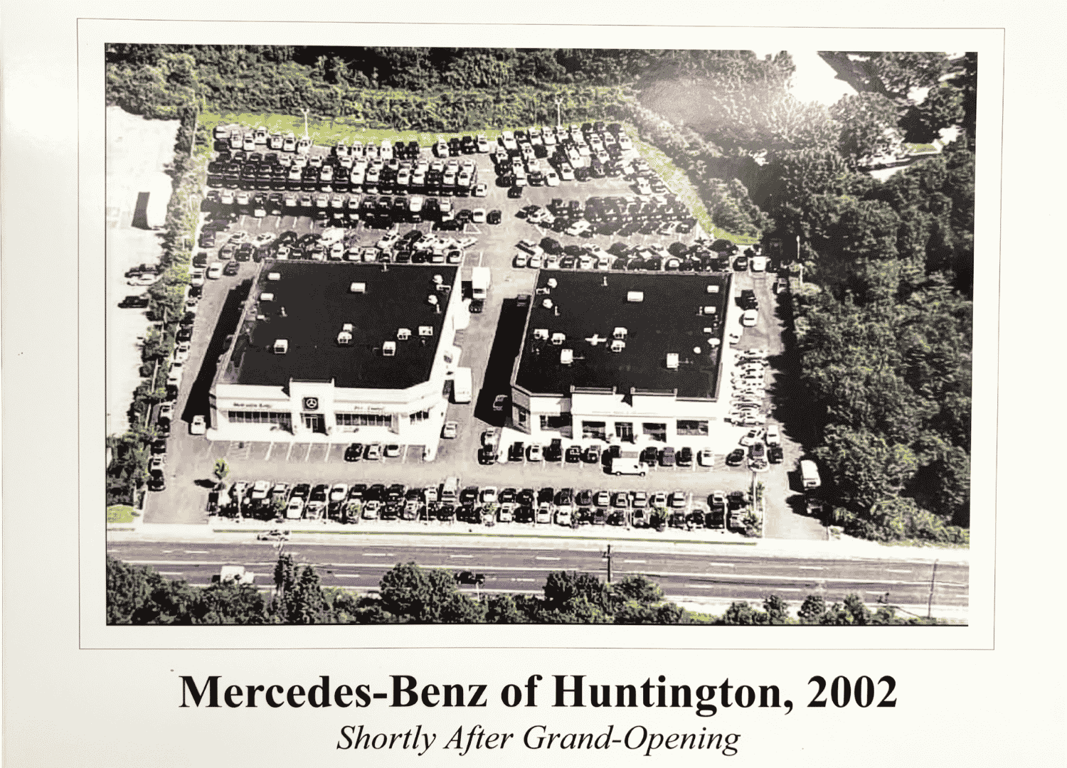 Aerial view of Mercedes-Benz of Huntington dealership, with two flat-roofed buildings, and rows of cars in parking lots.