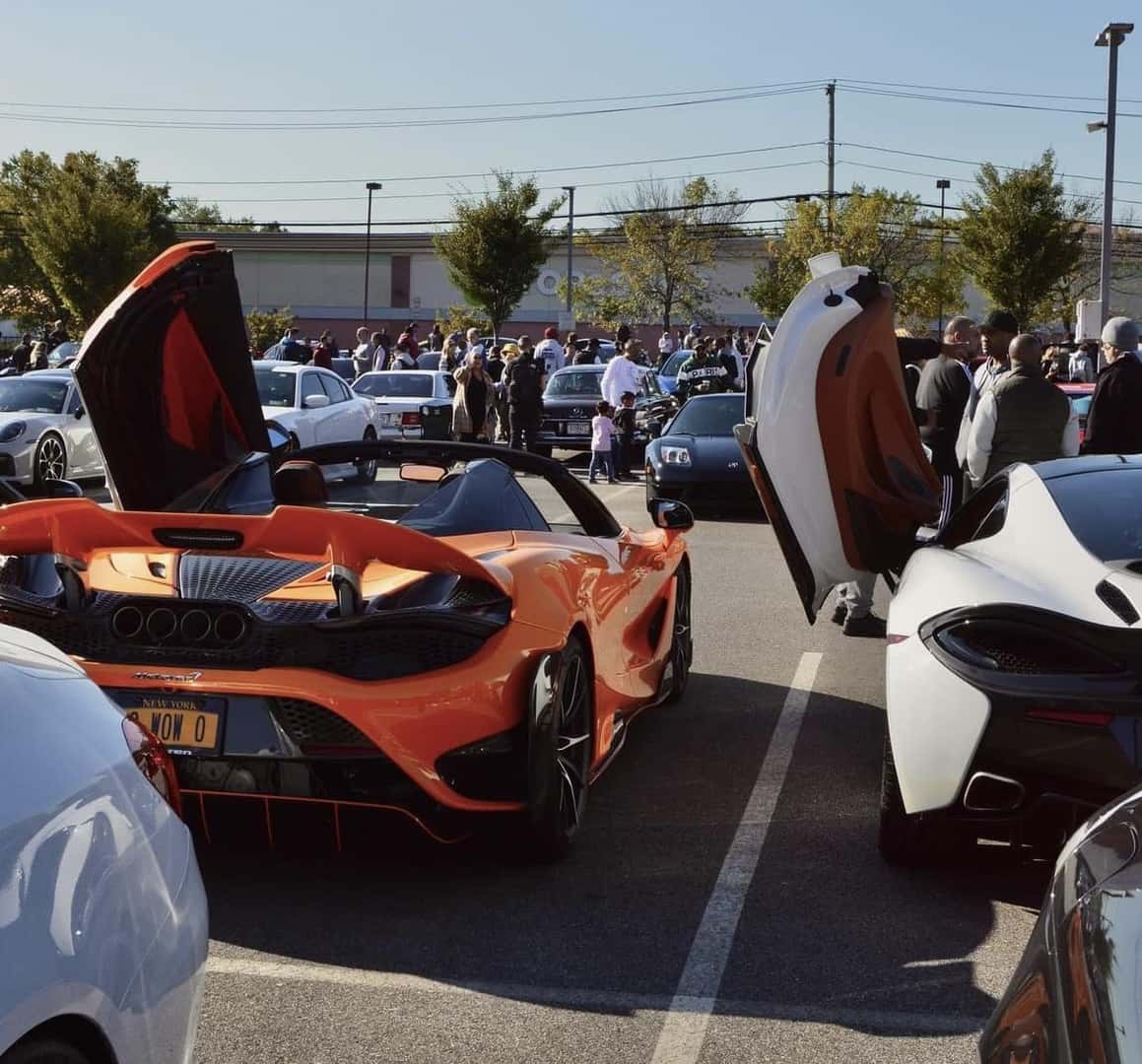 Orange McLaren 765LT Spider and a white McLaren 570S with doors raised among the show cars