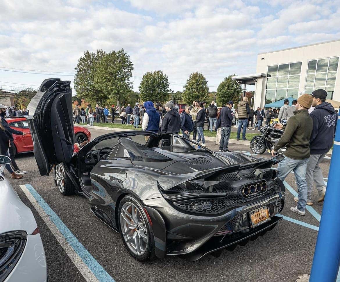 Dark gray McLaren 765LT Spider with its butterfly doors up drawing a crowd of onlookers