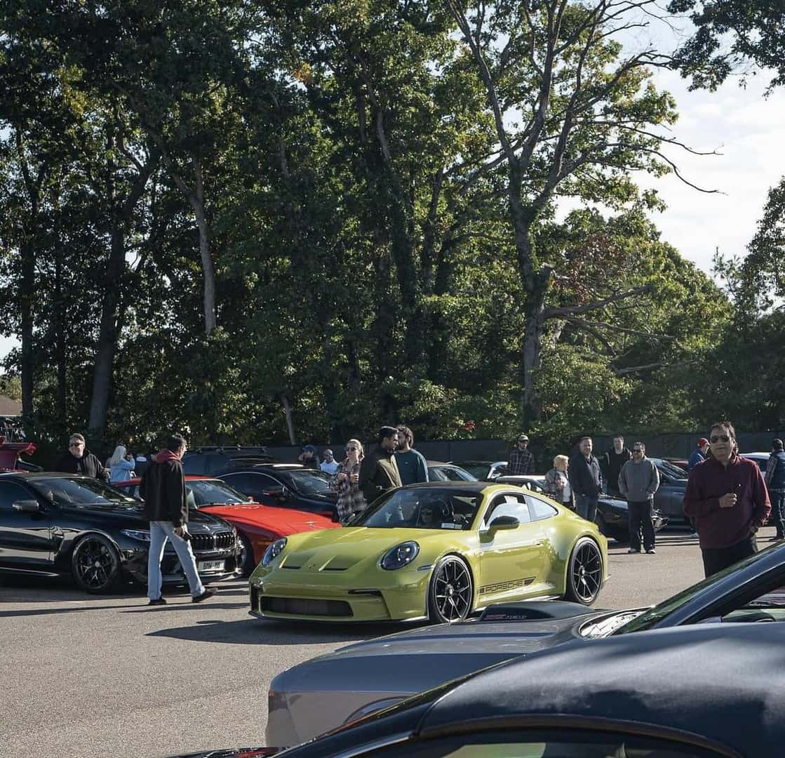 Yellow-green Porsche 911 GT3 driving past spectators and parked sports cars