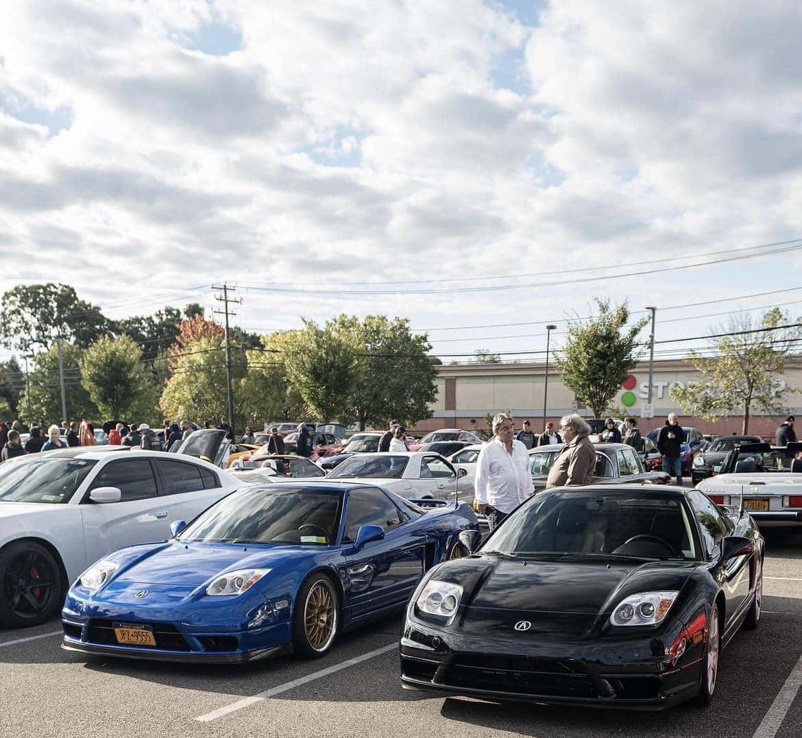 Blue and black Acura NSX coupes parked side by side as guests look on