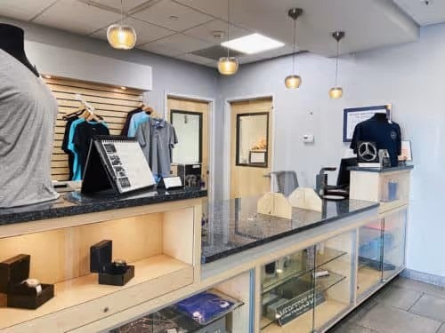 A bright retail store counter with clothing displays, a reception desk, and glass display cases