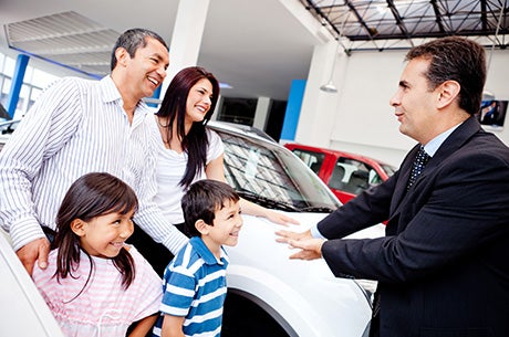 Family with dealership representative beside a vehicle