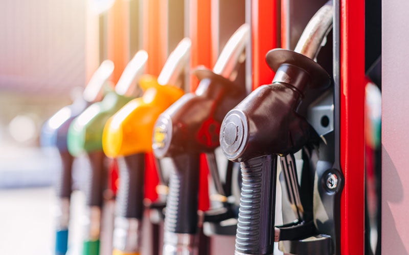 Row of colorful fuel pump nozzles mounted on a gas station pump, with focus on the black nozzle in the foreground