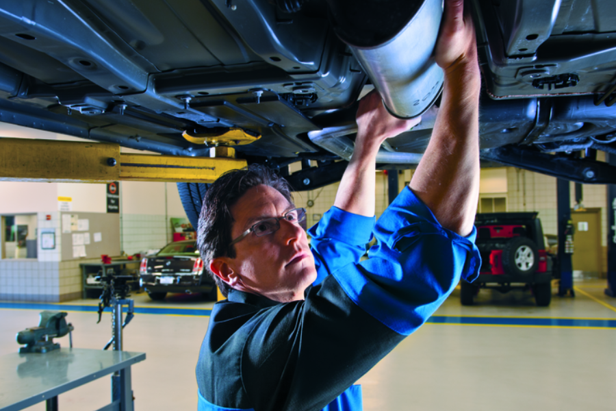 Technician servicing vehicle underside