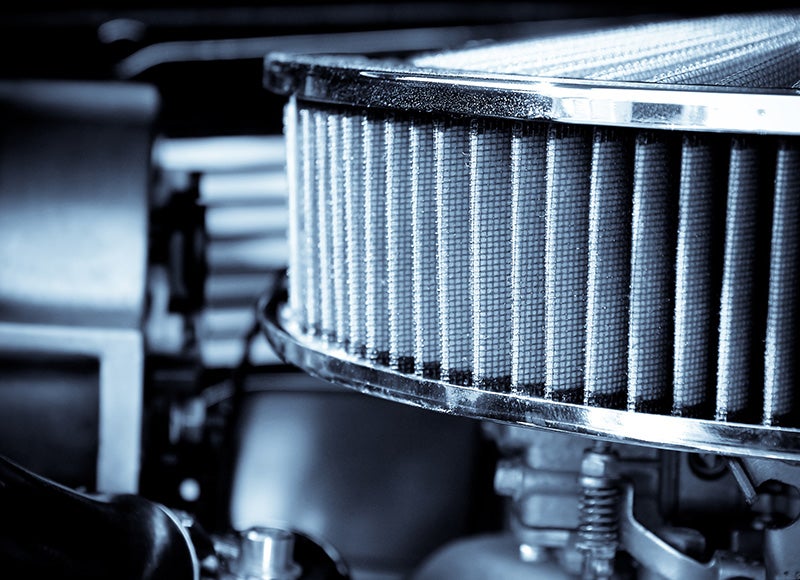 Close-up of a cylindrical engine air filter with pleated filter material inside a vehicle engine bay