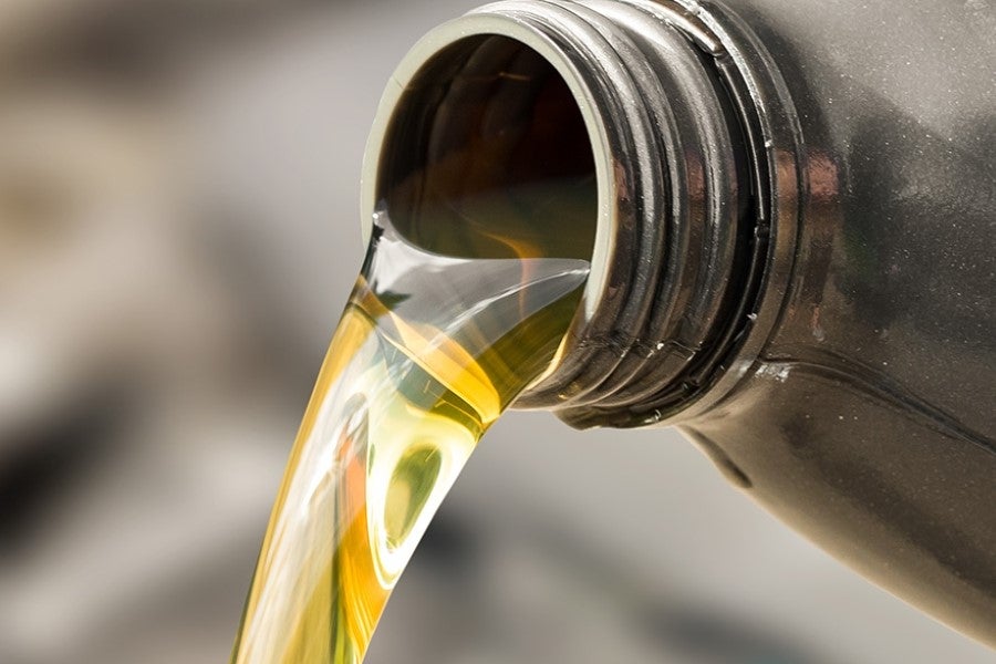Close-up of golden engine oil being poured from a motor oil container